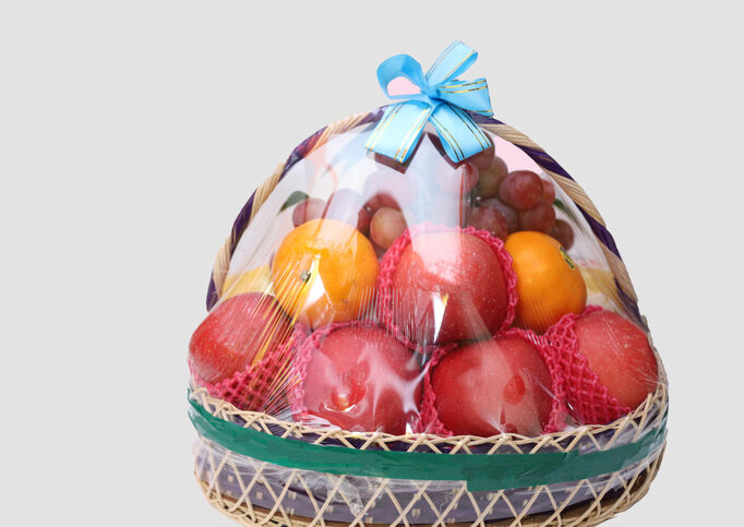 A basket of fruit is wrapped in plastic.