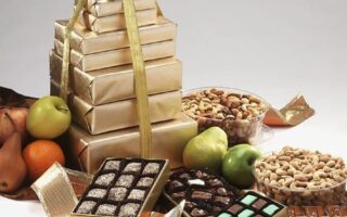 A stack of gold wrapped gifts next to nuts and apples.