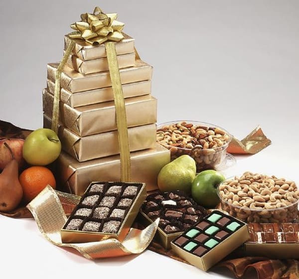 A stack of gold wrapped gifts next to nuts and apples.