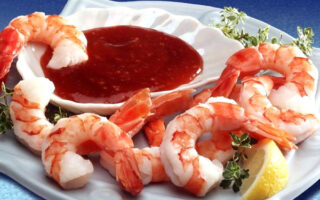 A plate of shrimp with sauce on the side.