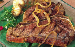 A steak with onions and mushrooms on the side.