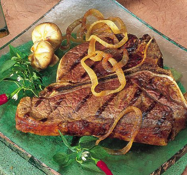A steak with onions and mushrooms on the side.